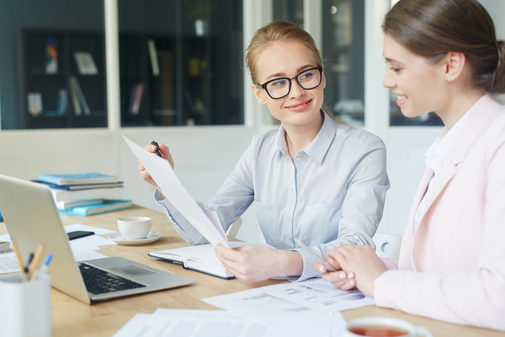 deux jeunes femmes souriantes regardes es documents comptables